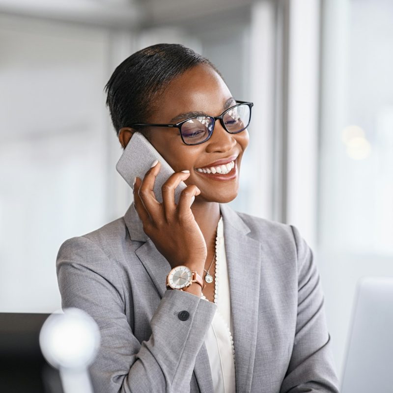 Successful african business woman talking on phone in office